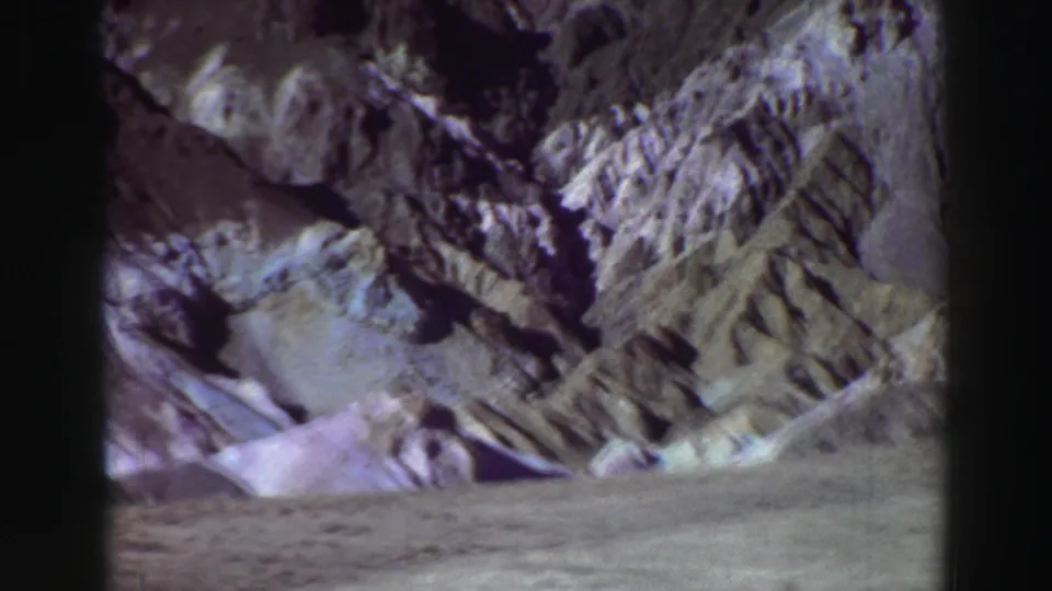 1969 Lake Tahoe landscape frame with layered rock formations, bright ground, and visible 8mm color fading.