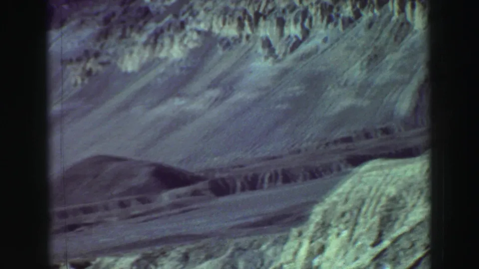 Vintage 8mm view of layered, arid-looking hills and a winding track, from footage cataloged as Lake Tahoe, California in 1969.