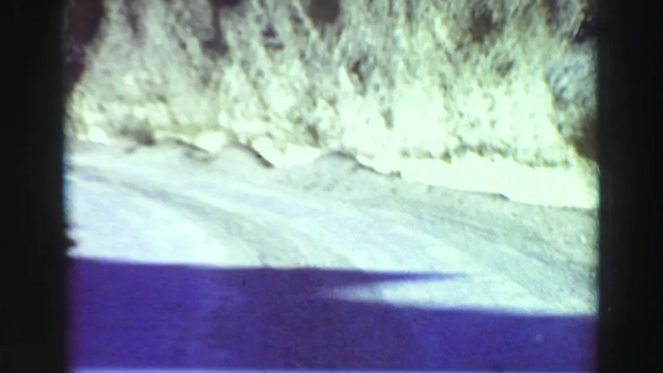 Overexposed 8mm frame of a rough mountain road beside a pale rocky bank in the Lake Tahoe area.