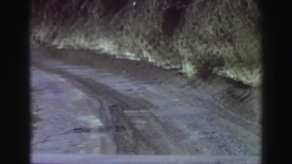 A rutted mountain road near Lake Tahoe in 1969, seen from a moving 8mm home-movie perspective beside rough rock faces.