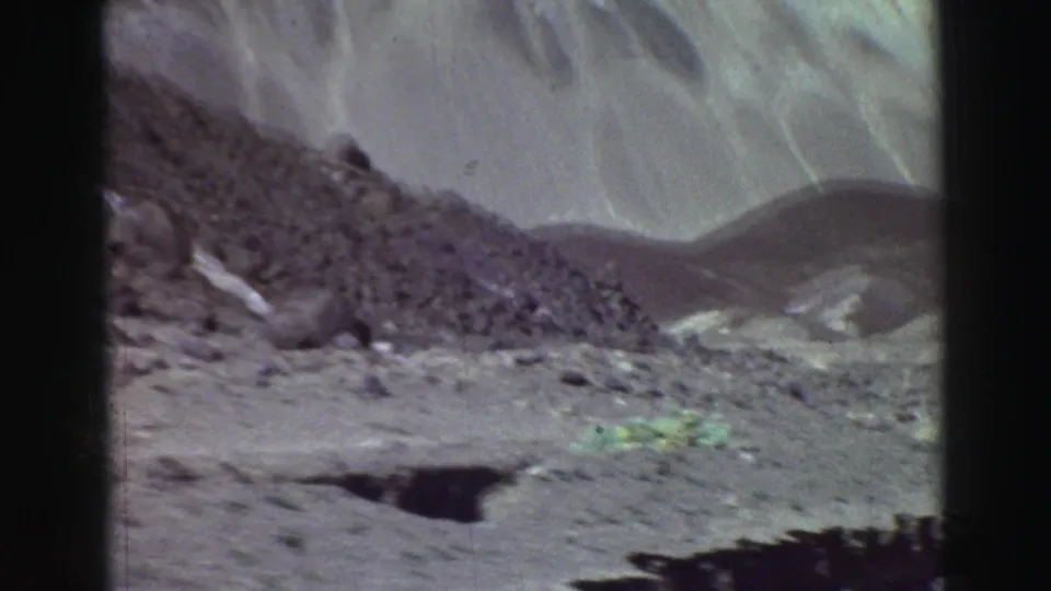A Lake Tahoe-area mountain road in 1969 with a rocky foreground, pale dirt surface, and distant slopes beyond the roadside.