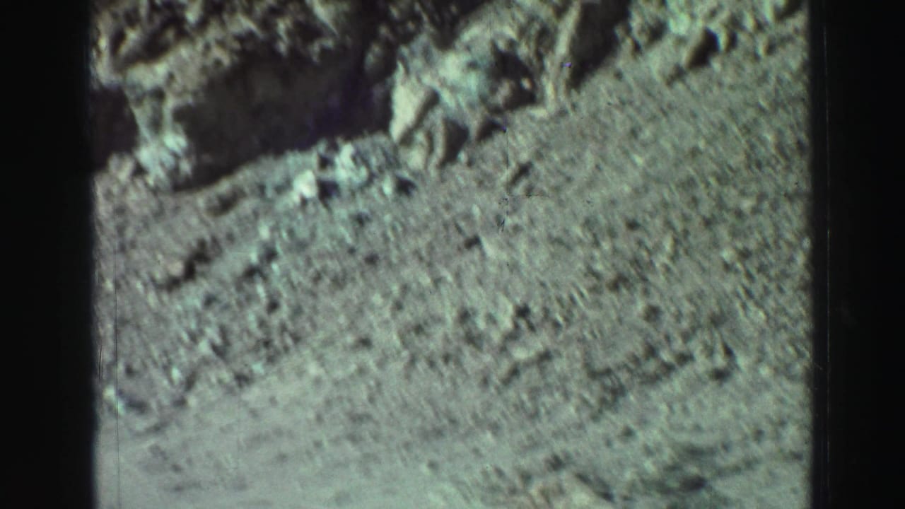 Rocky dirt slope with scattered stones and a darker rock edge at the top.