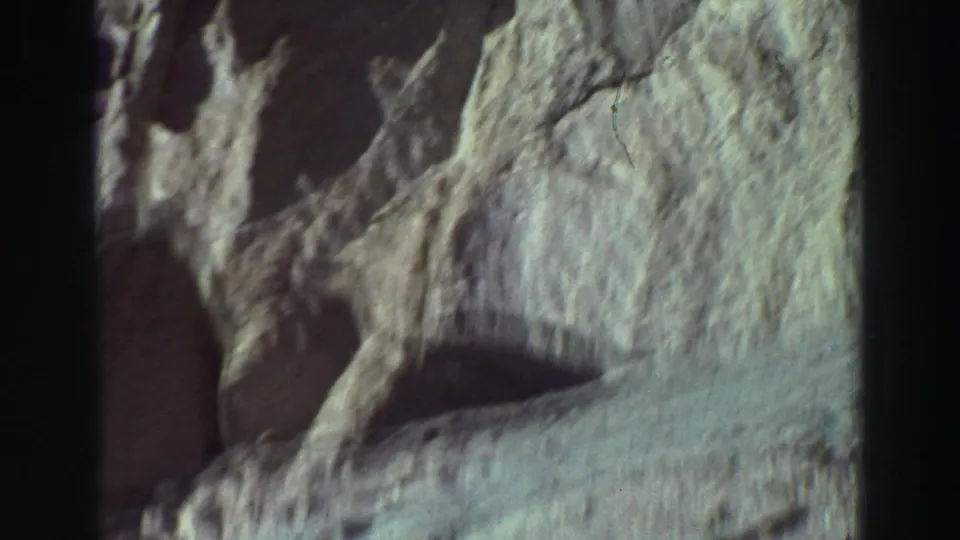 1969 Lake Tahoe 8mm frame with a weathered rock face and a sloping dirt surface beneath it.