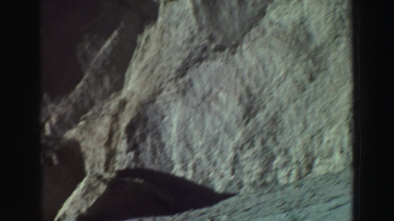Rock formation with a dark shadowed opening and visible film-frame borders.