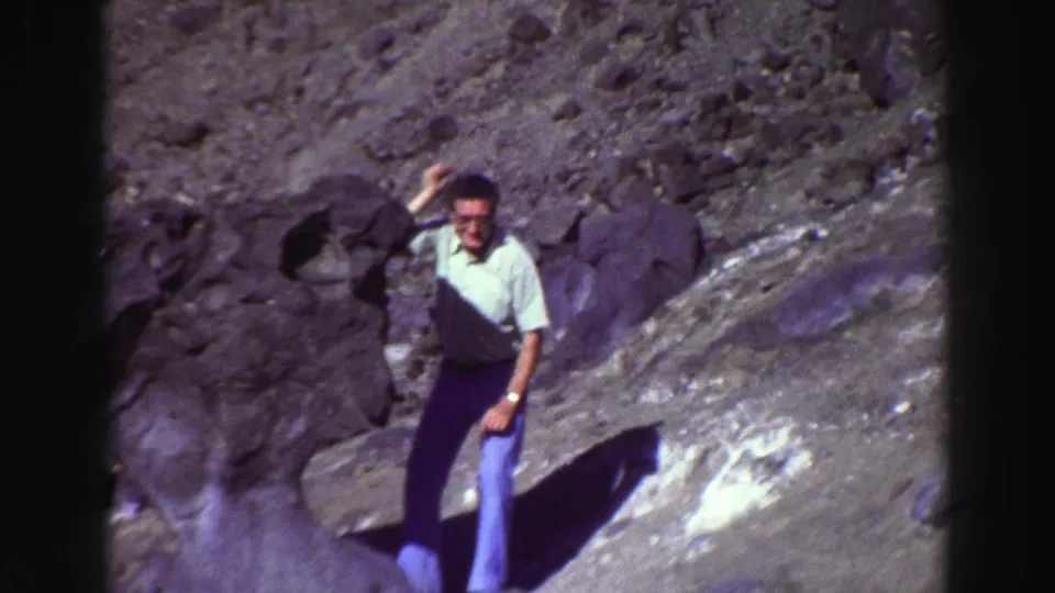 1969 Lake Tahoe frame of a man posing on uneven rocks, with one hand raised near his hair and strong sunlight casting shadows.