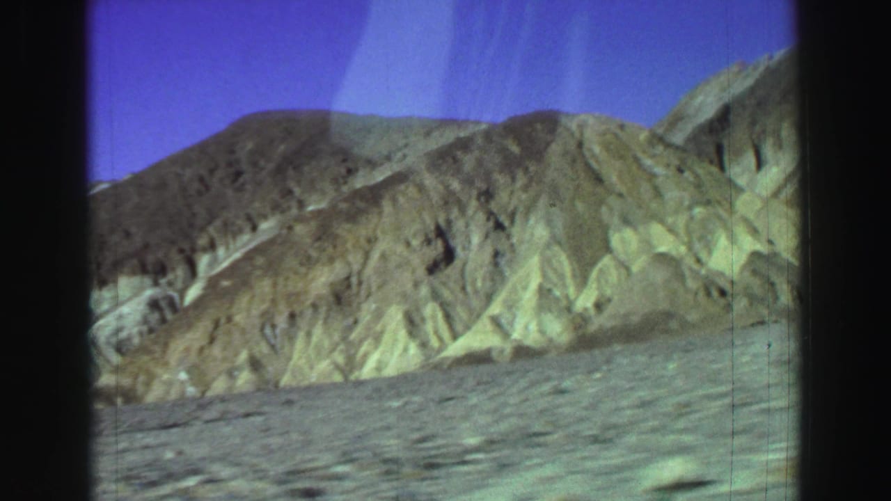 Barren foreground and layered desert mountains beneath a deep blue-purple sky.