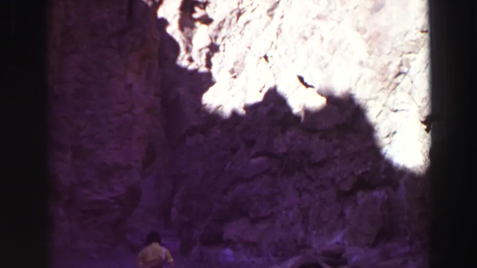 1969 Lake Tahoe-area canyon view with purple-tinted rock walls and a partially visible walker near the bottom of the frame.
