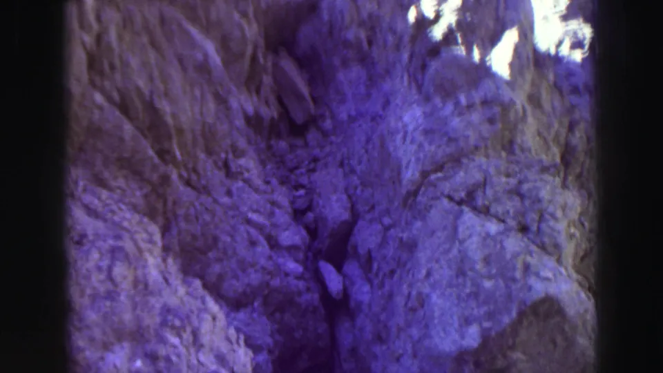 Color-shifted 8mm frame from Lake Tahoe in 1969 showing a steep rocky passage, shadowed stone, and bright highlights near the top.