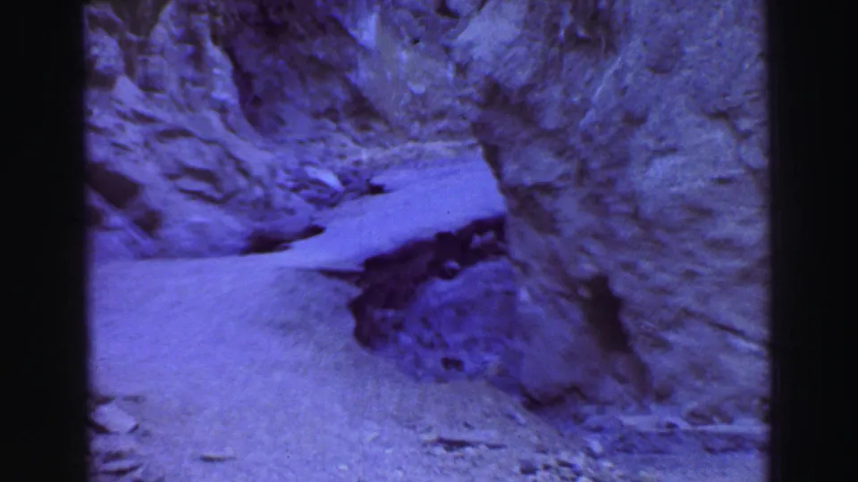 1969 Lake Tahoe 8mm frame looking across pale ground or snow-like terrain at the base of steep rocky walls.