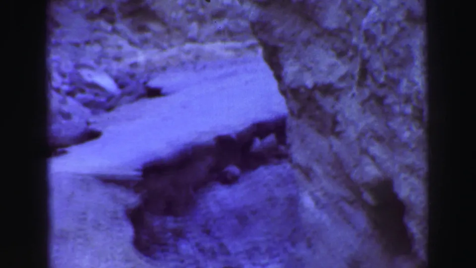 1969 Lake Tahoe frame showing a pale slope at the base of rocky terrain, with dark shadowed rock and visible film borders.