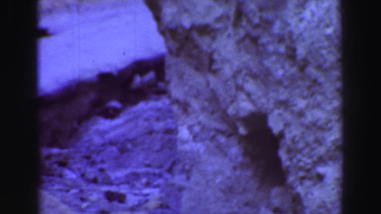 Close-up of rough rock surface with purple color cast and dark film borders.