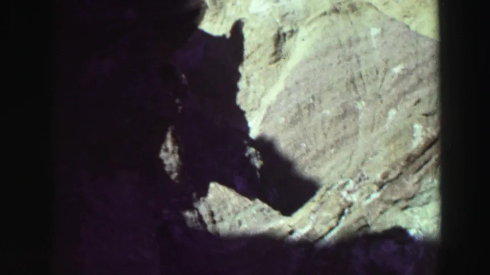 1969 8mm Lake Tahoe close-up of bright stone and a dark central crevice, with faded color, soft detail, and black film edges.