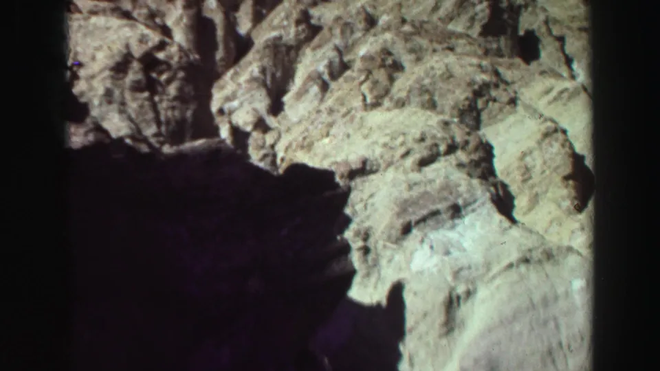 1969 8mm Lake Tahoe view of eroded canyon stone, with dark shadow across the lower frame and sunlit pale rock above.