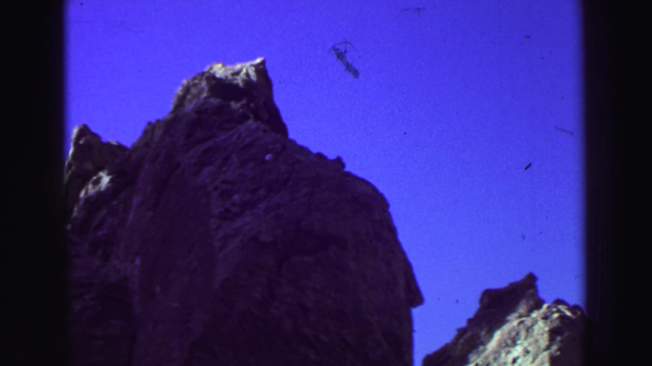 Low-angle view of jagged rock peaks against a saturated purple sky.