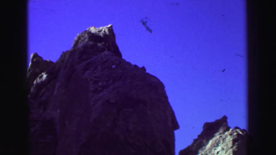 1969 Lake Tahoe 8mm frame showing a low-angle view of jagged gray rock peaks silhouetted against a deep purple sky.