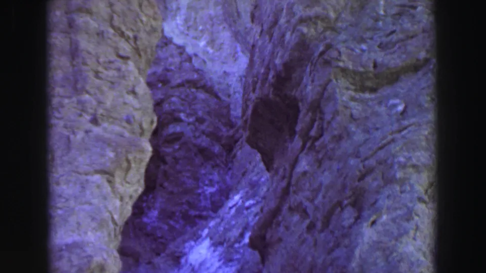 1969 Lake Tahoe 8mm frame showing a narrow rock opening with dark shadowed crevice and pale gray stone along the sides.