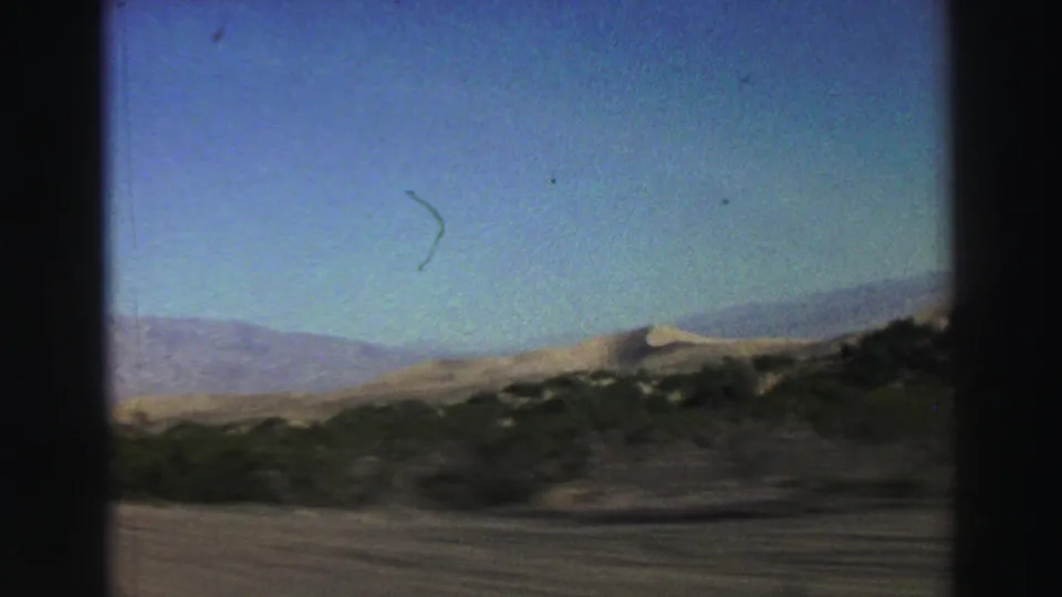 Lake Tahoe trip footage showing distant mountains, pale hillside, scrub foreground, and blue sky from a moving car in 1969.