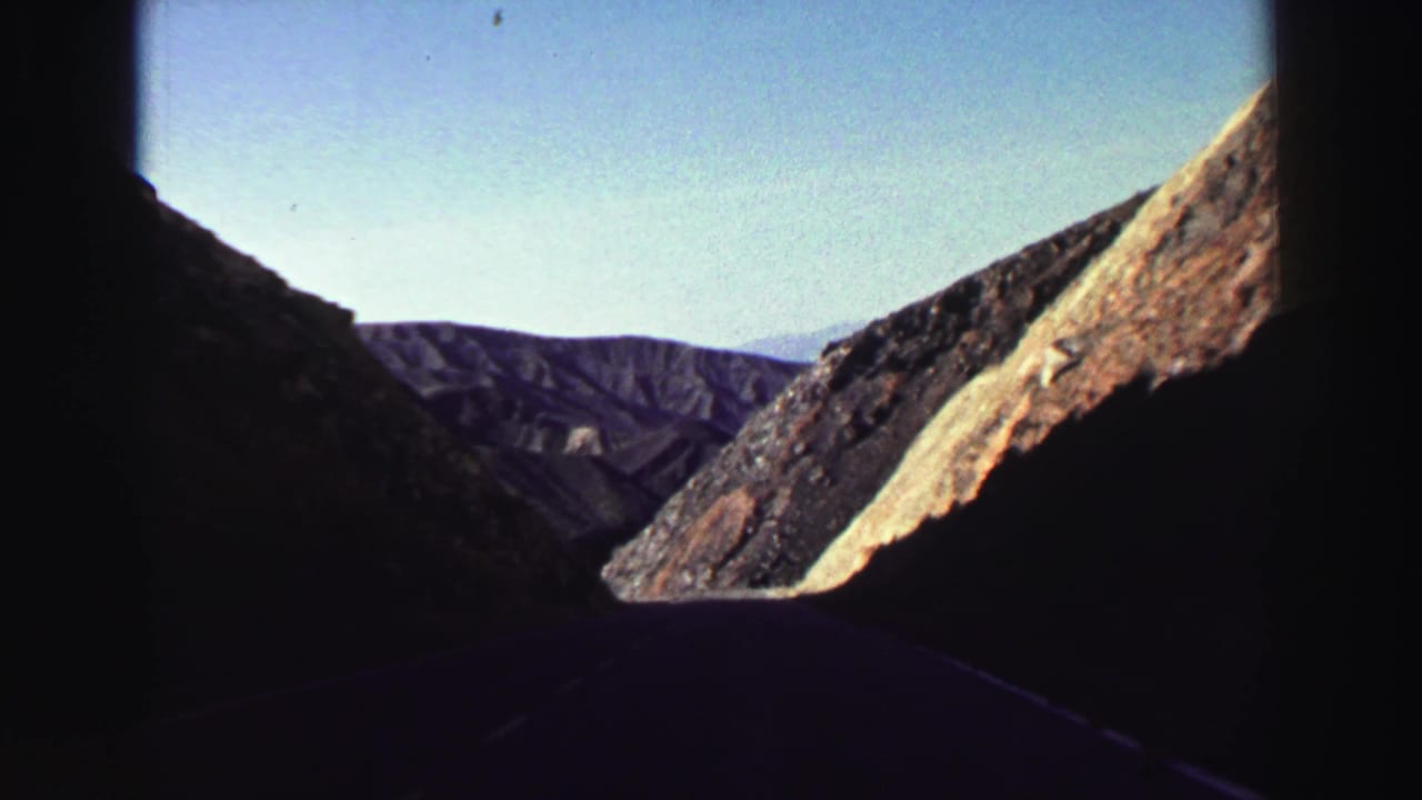 Rocky mountain slope and distant ridges seen through an 8mm film frame.