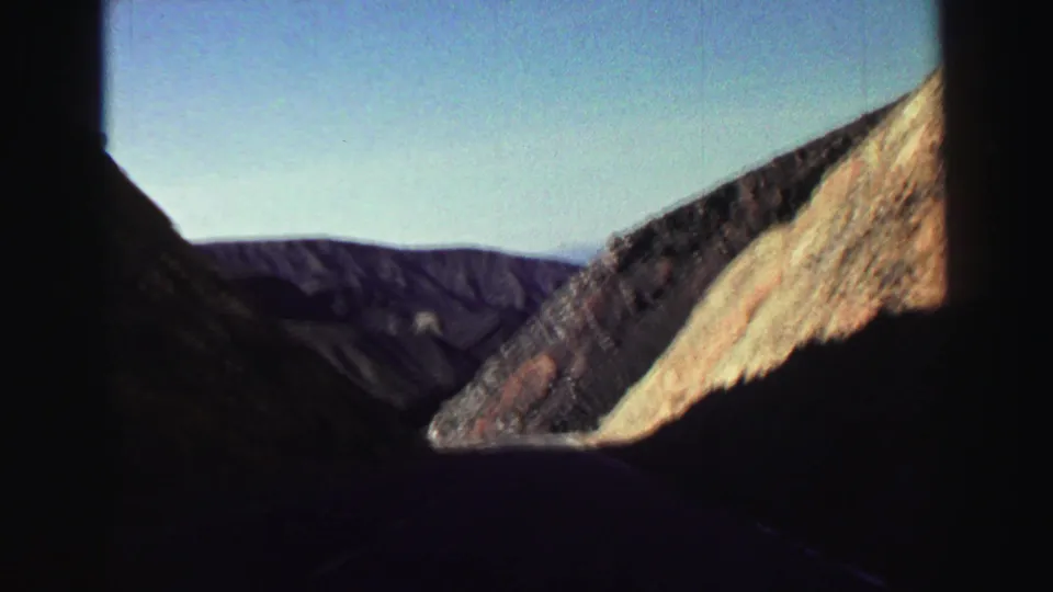 1969 Lake Tahoe-area travel footage looking across steep rock formations toward layered mountain ridges under clear sky.