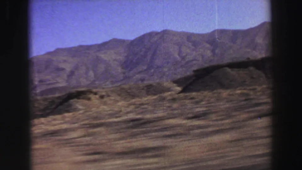 A 1969 8mm travel frame shows dry foreground terrain streaking past a mountain ridge in the Lake Tahoe, California metadata setting.