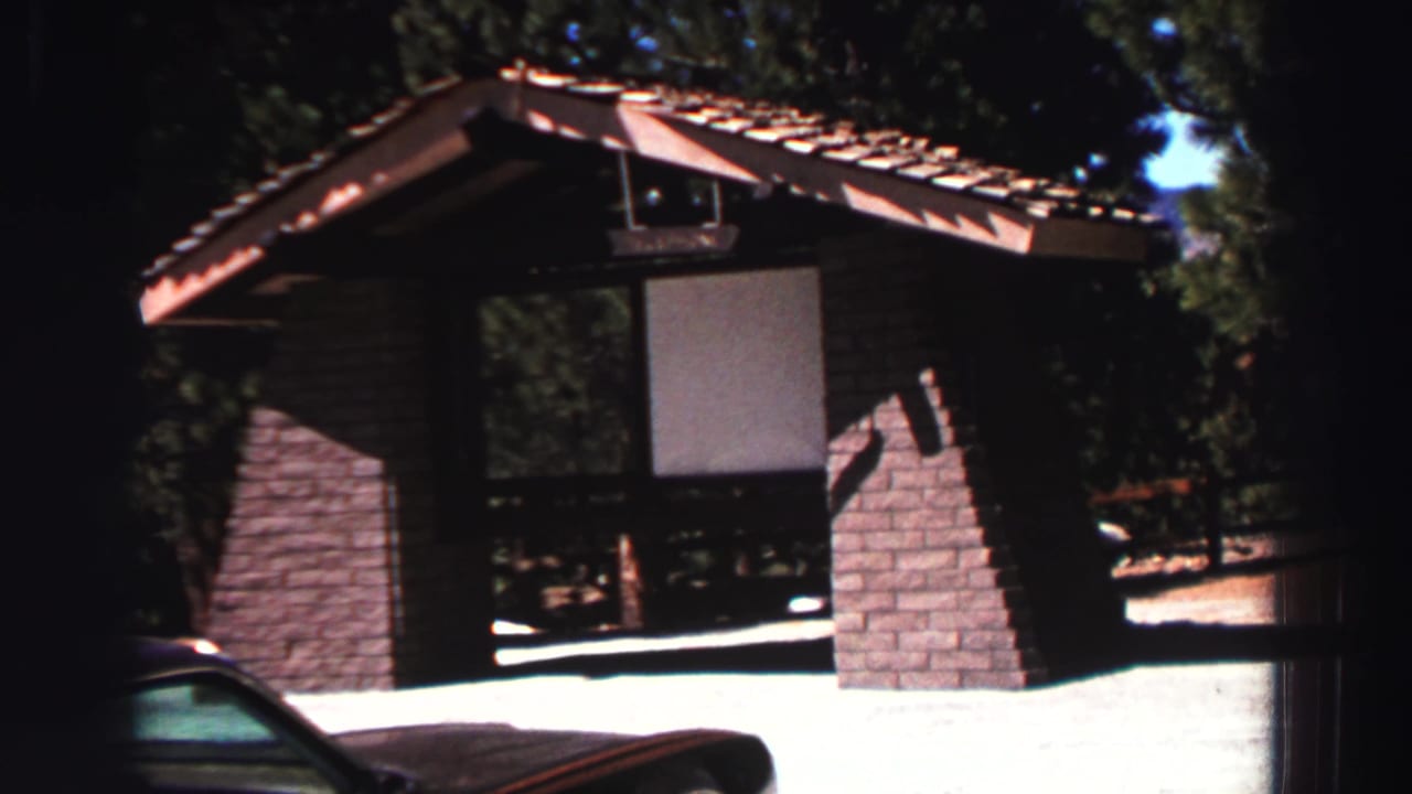 Rustic brick-and-wood shelter with a tiled roof beside a partly visible car.