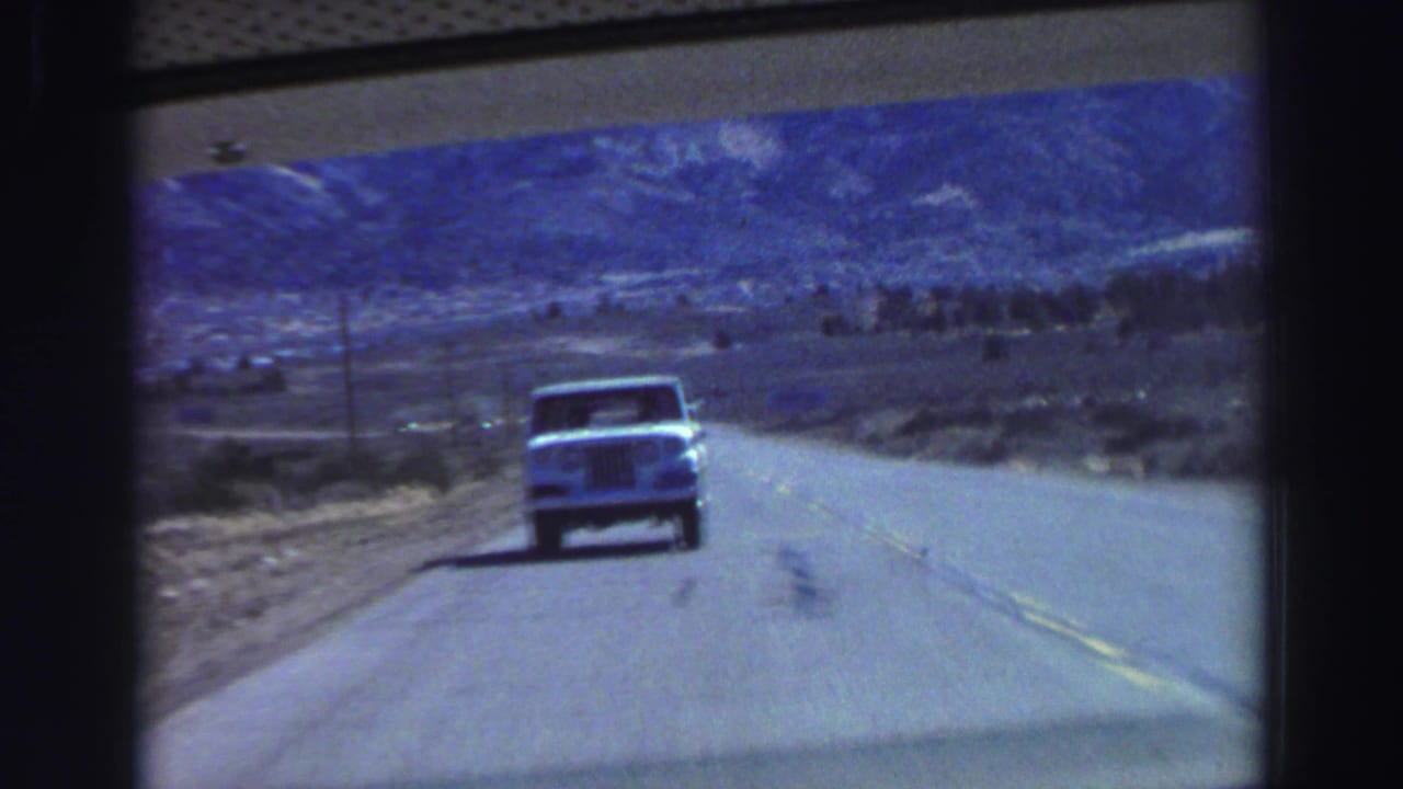 Lake Tahoe-area road-trip view from inside a moving vehicle, with a light truck on the highway and mountains ahead.