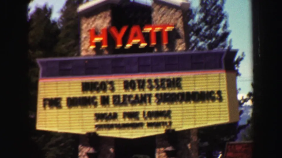 1969 Lake Tahoe footage showing a Hyatt sign and marquee for dining and entertainment, with trees and water behind it.