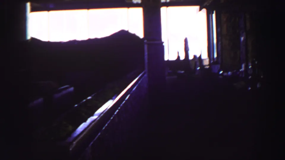 1969 Lake Tahoe frame showing a dim interior with bright windows and silhouetted railing, possibly near a scenic overlook.