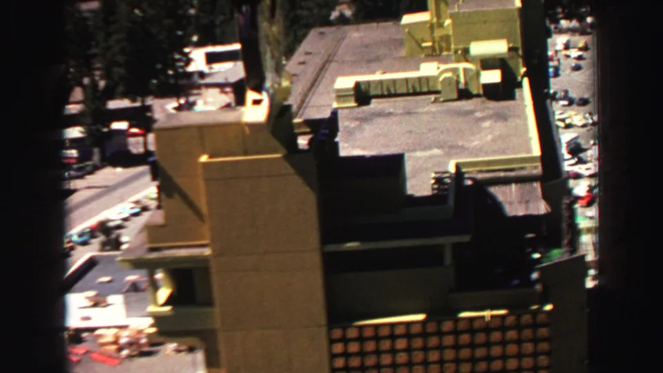 High 1969 Lake Tahoe view showing a large flat-roofed building, paved roads, and parked cars in bright sun.