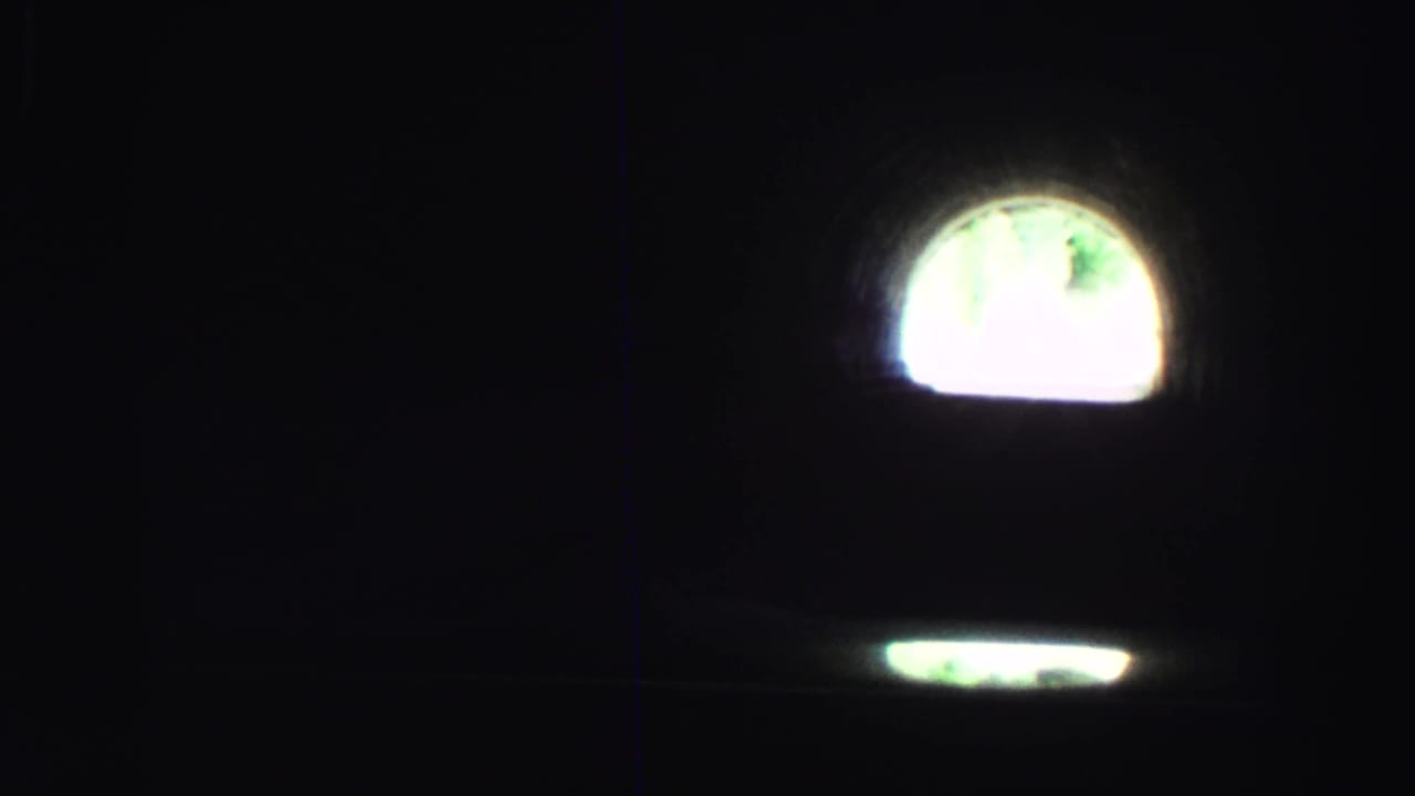Dark tunnel interior with a bright arched opening ahead.