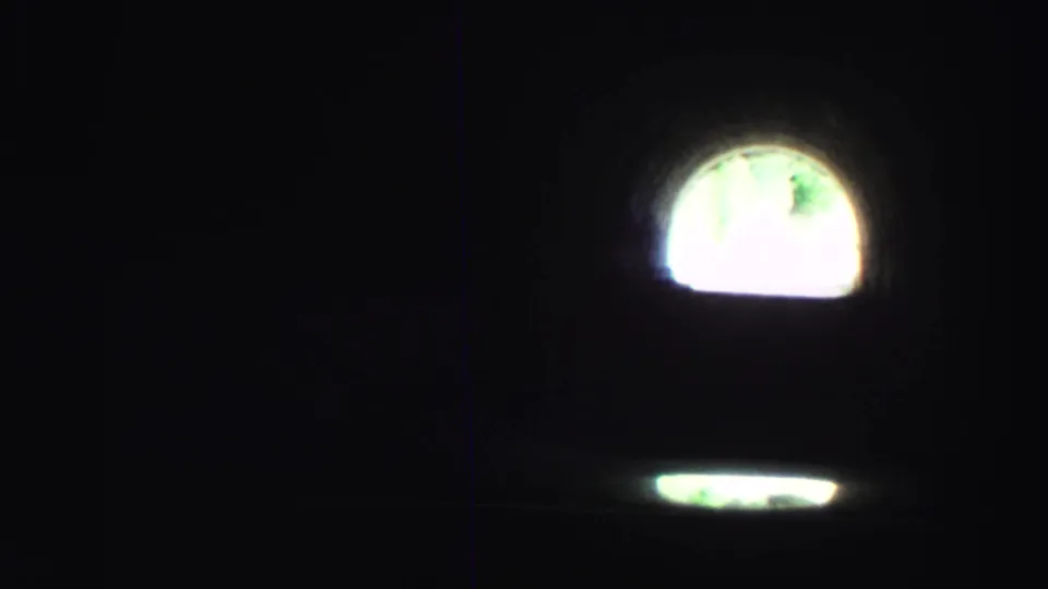 1969 8mm Lake Tahoe driving view from inside a dark tunnel, looking toward a bright arched exit.