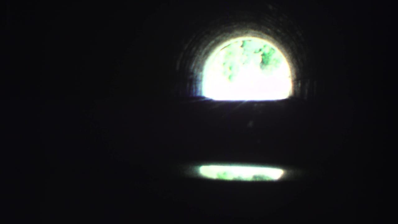 Bright arched tunnel opening above a dim road view.