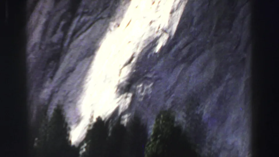 1969 Lake Tahoe 8mm frame showing a sheer rock face with a bright vertical sunlit area and deep shadow along the cliff.