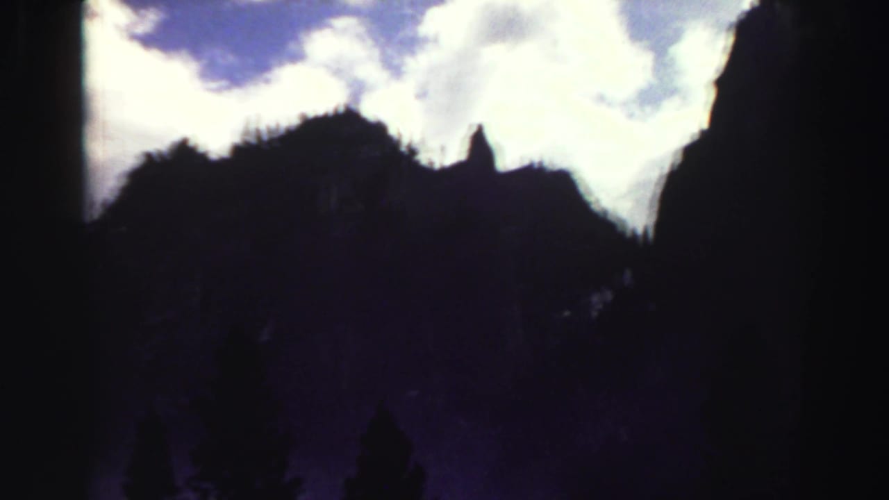 Dark mountain ridge and cloudy sky seen through soft, high-contrast film exposure.