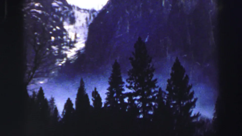 Lake Tahoe-area mountain and evergreen view on color 8mm, with blue haze and bright patches on distant slopes.