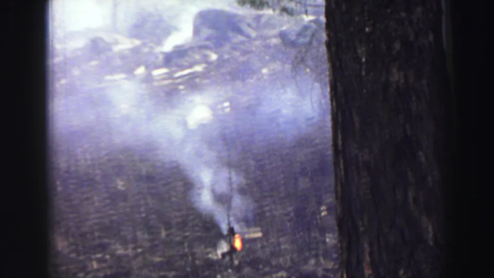 Smoke billows from a small fire on forested ground in the Lake Tahoe area, filmed on 8mm in 1969.