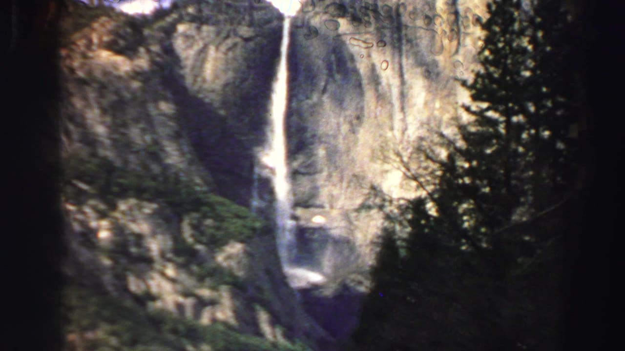 Lake Tahoe-area 8mm travel frame with a tall waterfall descending a granite cliff behind silhouetted evergreens.