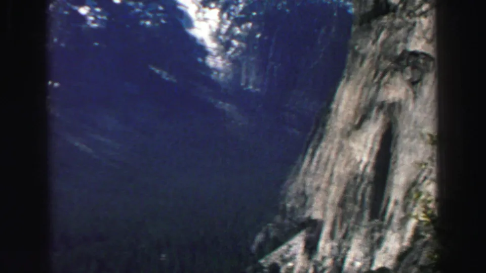 Lake Tahoe area 8mm view of a steep cliff face and forested valley, with deep blue shadow across the landscape.