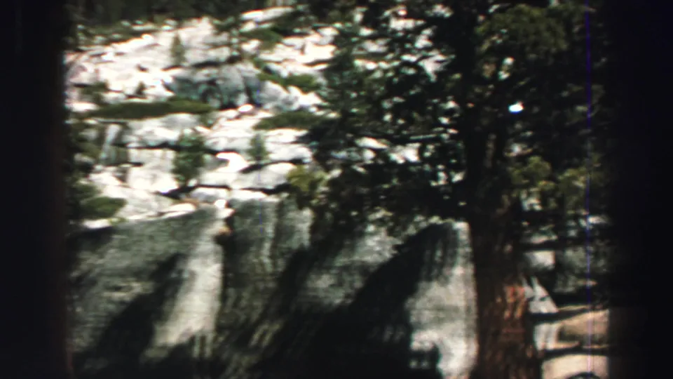 Lake Tahoe-area 1969 8mm frame showing evergreen trunks and pale granite rocks in bright mountain light.