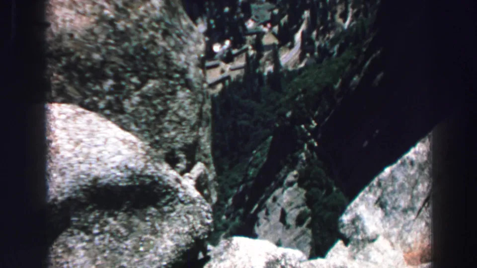 1969 Lake Tahoe frame showing a rocky valley, evergreen cover, and a small distant person moving through the terrain.