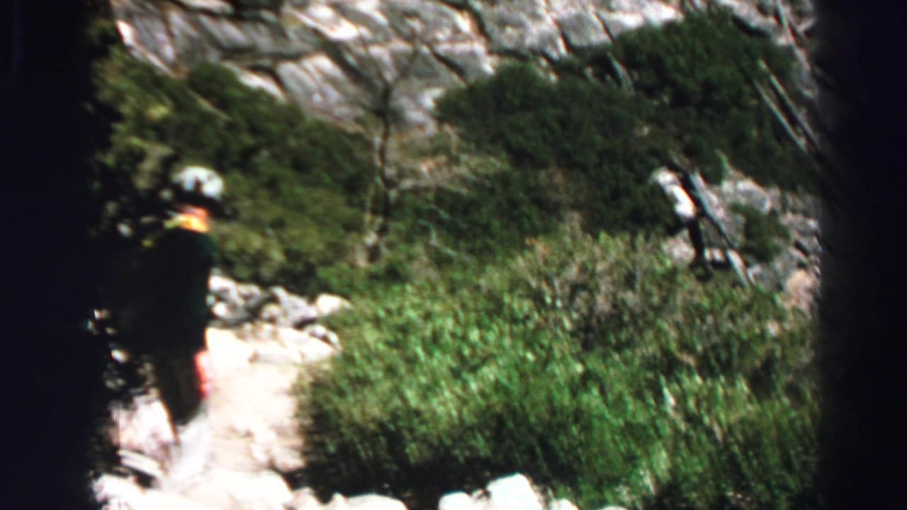 Lone scout-like hiker moves along a rocky Lake Tahoe forest trail in this 1969 8mm home-movie frame.
