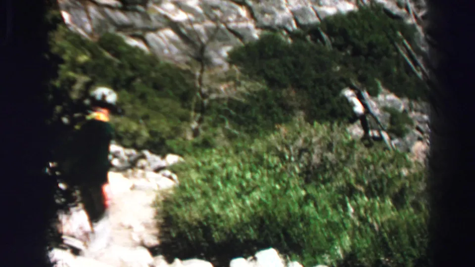 Lone scout-like hiker moves along a rocky Lake Tahoe forest trail in this 1969 8mm home-movie frame.