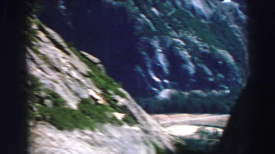 Lake Tahoe-area mountain view with granite slope, dark forest framing, and distant rugged terrain on 8mm film.