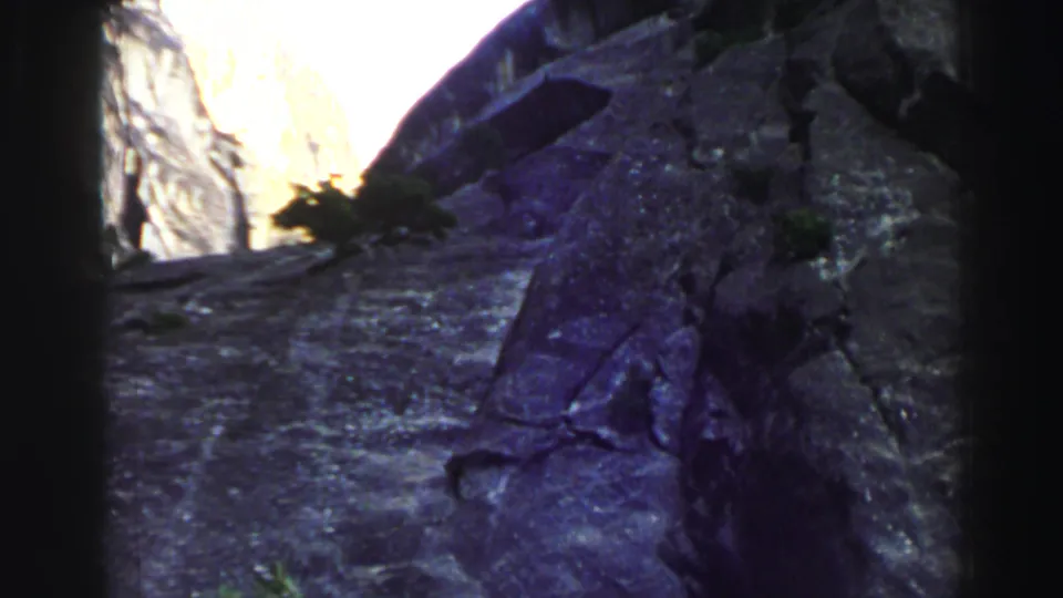 Vintage 8mm frame of the Lake Tahoe canyon showing shadowed stone, a bright sunlit opening, and slight color shift in the rock surface.