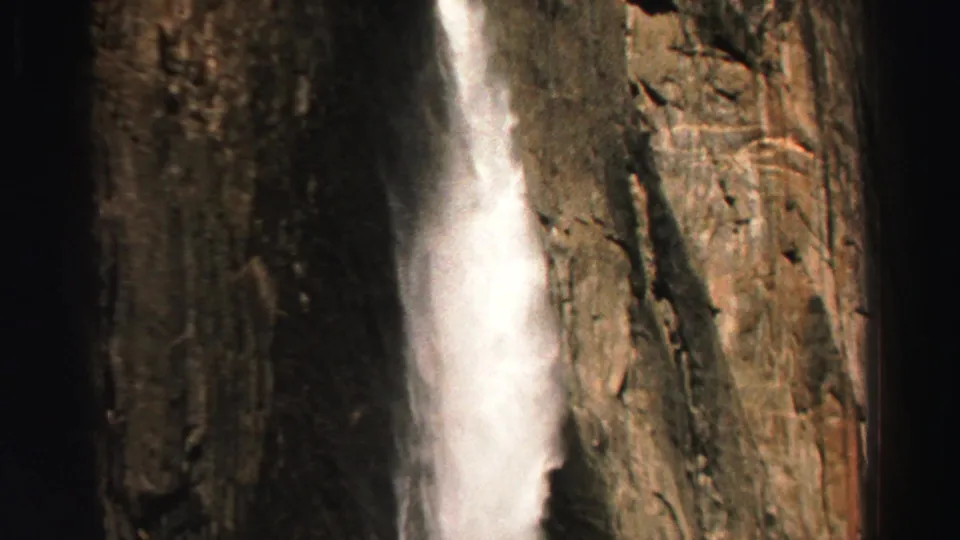1969 Lake Tahoe home-movie frame showing white water falling along a steep, textured rock face.