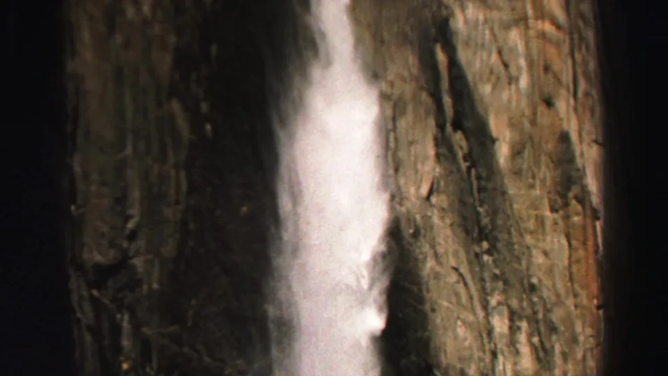 1969 Lake Tahoe 8mm frame with a narrow waterfall against massive vertical rock formations.