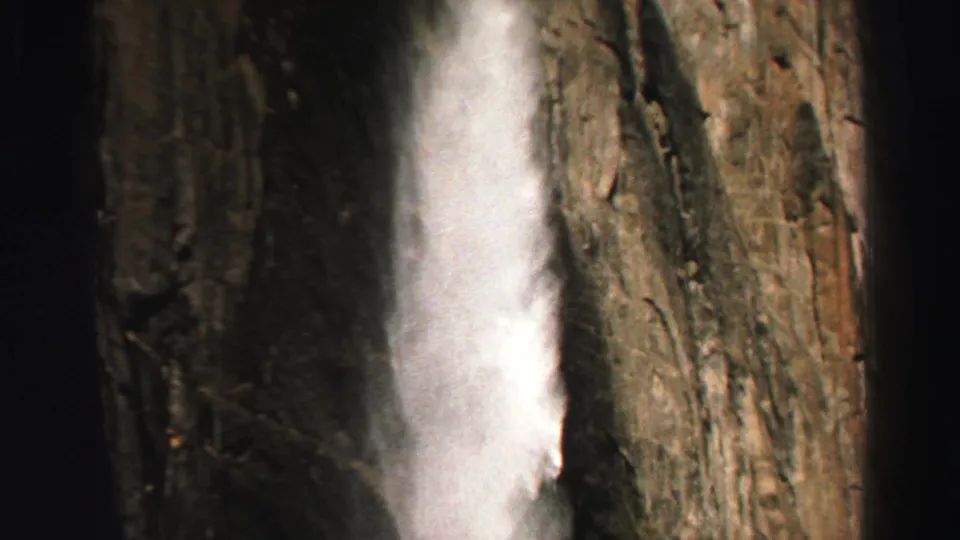 1969 Lake Tahoe frame showing a closer view of waterfall spray running down a rugged cliff face.