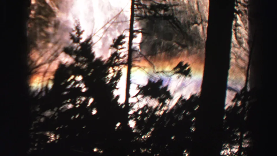 Lake Tahoe 8mm frame with waterfall spray, strong contrast, silhouetted trees, and a rainbow band in the mist.