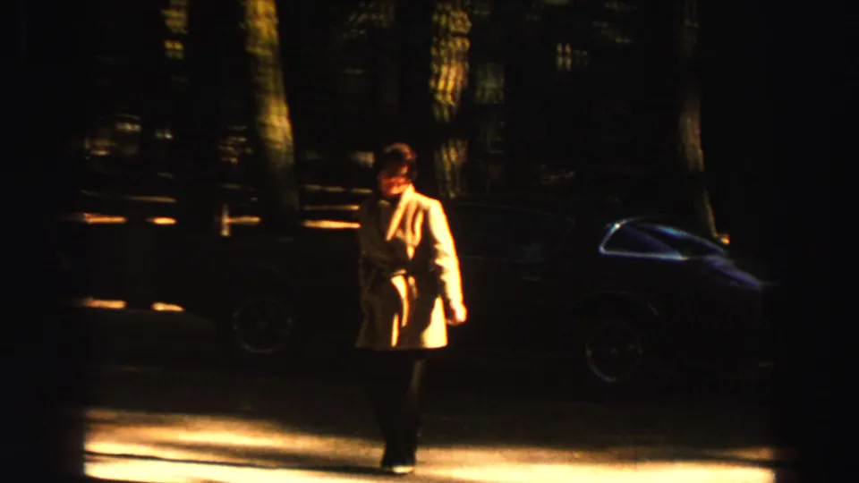 1969 Lake Tahoe roadside forest scene with an adult in a light coat walking past a dark parked car.