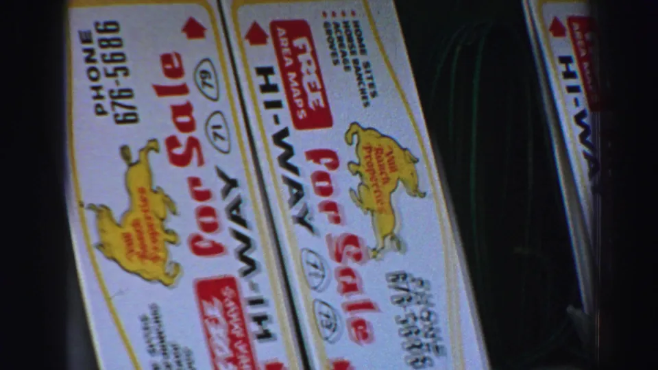 Close 8mm view of a tilted Lake Tahoe sale board with bold red text, a yellow horse logo and a visible phone number.